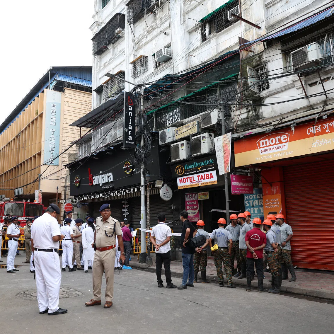 Firefighters and other officials stand on the street in the aftermath of hotel a fire that killed several people in Kolkata, India, on Aug 19.