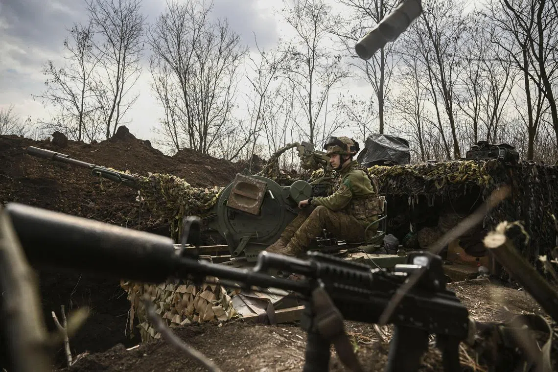 A Ukrainian serviceman sits on an anti-aircraft gun, near Bakhmut, on March 24, 2023.