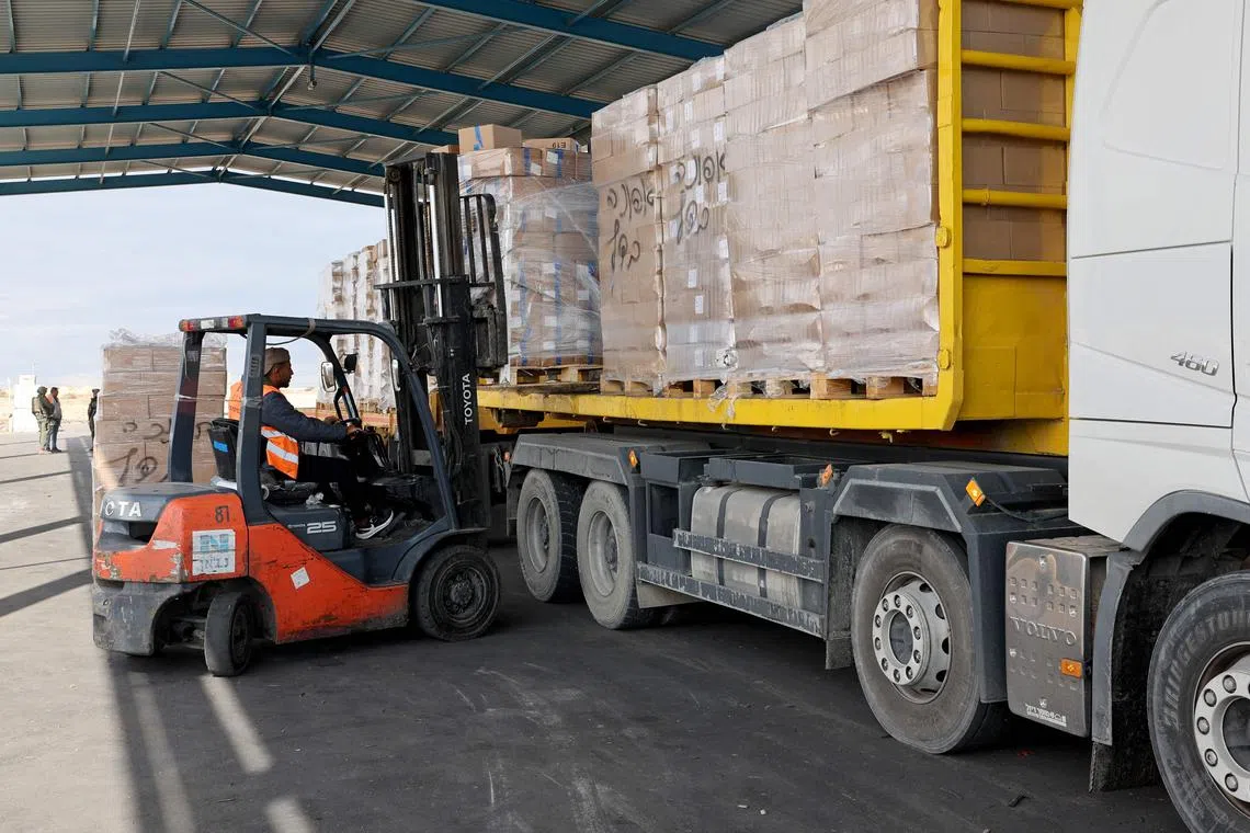 A picture taken during a tour organised by the Israeli Army shows a Palestinian worker unloading humanitarian aid for the Gaza Strip from a truck near the Kerem Shalom crossing, also known as Karm Abu Salem, on November 28, 2024, amid the ongoing conflict in the Palestinian territory between Israel and the militant group Hamas. (Photo by JACK GUEZ / AFP)