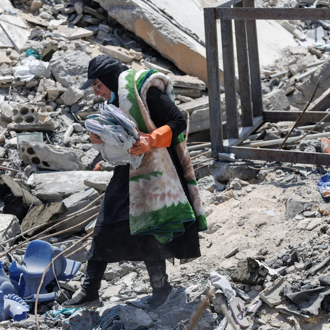 Nour Hamzeh carries her children's belongings salvaged from the rubble of her home, which was destroyed in an Israeli strike, after returning to Zawtar al-Gharbiyeh in southern Lebanon following the deployment of Lebanese soldiers in one of three so-called pilot zones established after the withdrawal of Israeli forces under a U.S.-brokered plan, July 27, 2026. REUTERS/Zohra Bensemra