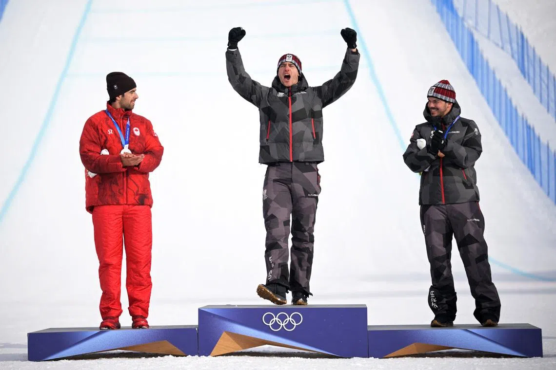 Milano Cortina 2026 Olympics - Snowboard - Men's Snowboard Cross Victory Ceremony - Livigno Snow Park, Livigno, Italy - February 12, 2026. Gold medallist Alessandro Haemmerle of Austria celebrates on the podium with silver medallist Eliot Grondin of Canada and bronze medallist Jakob Dusek of Austria REUTERS/Dylan Martinez