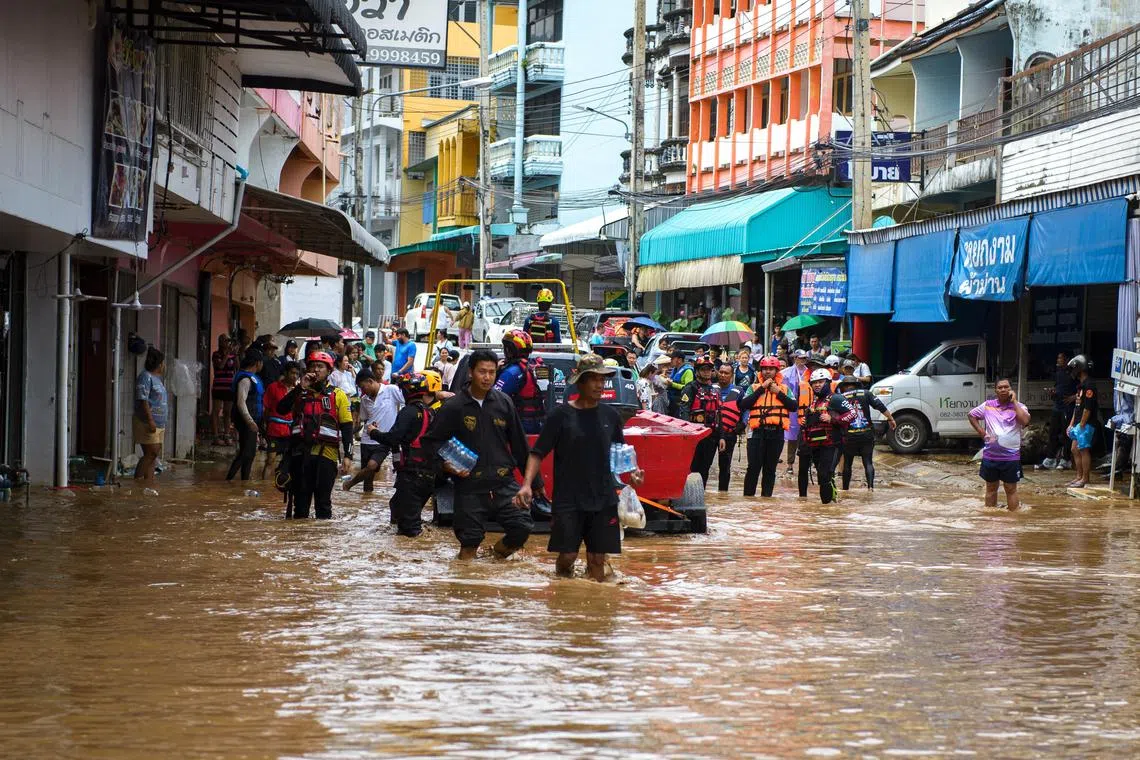 Rescue workers help stranded people from a flooded area at the border town of Mae Sai, following the impact of Typhoon Yagi, in the northern province of Chiang Rai, Thailand, September 11, 2024. REUTERS/SZZW
