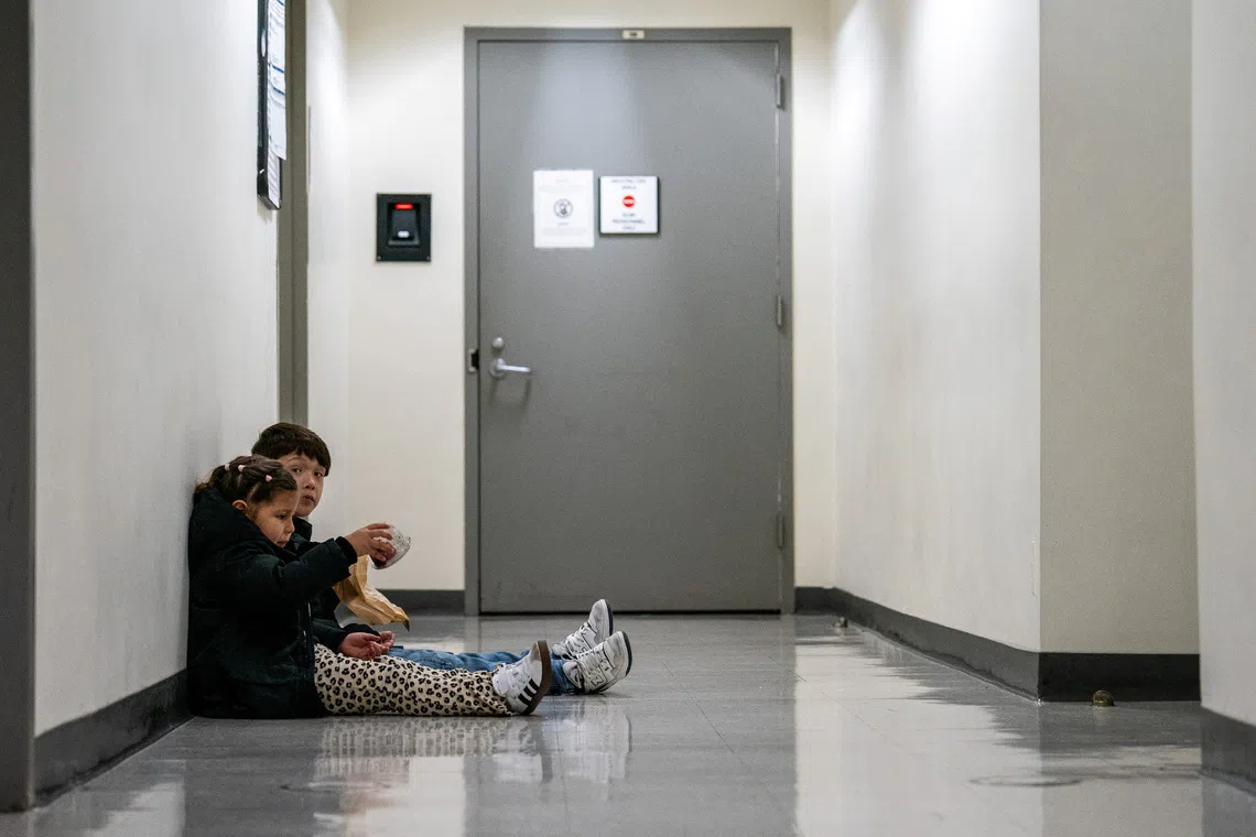 Two children sit in the hallway as their parents attend an immigration hearing at U.S. immigration court in Manhattan, in New York City, U.S., October 24, 2025. REUTERS/David 'Dee' Delgado