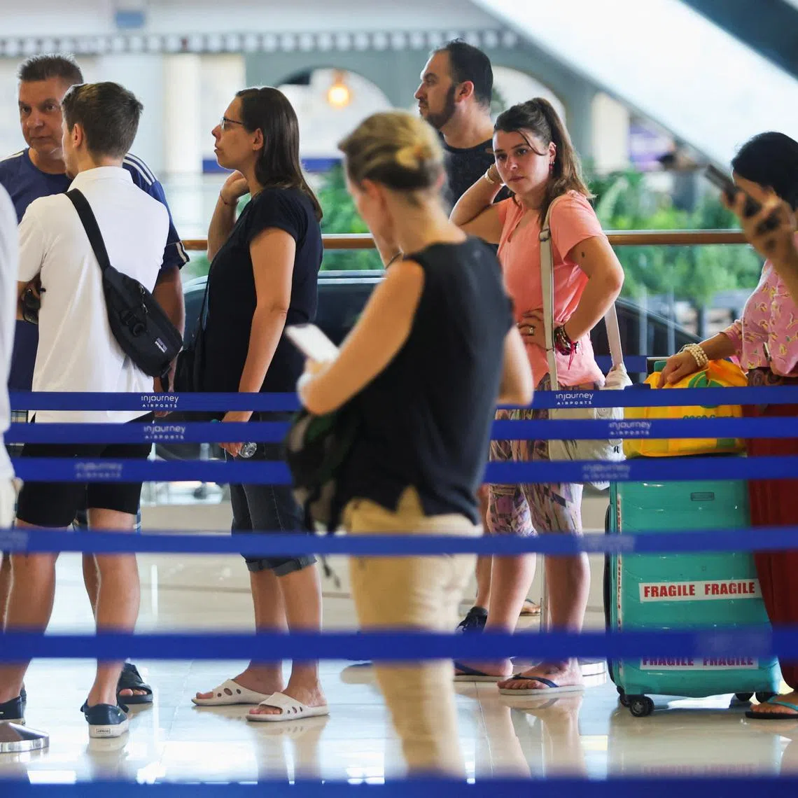 Stranded passengers stand in line at the Qatar Airways customer service at I Gusti Ngurah Rai International Airport after flights to Doha, Dubai, and Abu Dhabi were cancelled following strikes on Iran launched by the United States and Israel, in Kuta, Bali, Indonesia, March 1, 2026. REUTERS/Johannes Christo