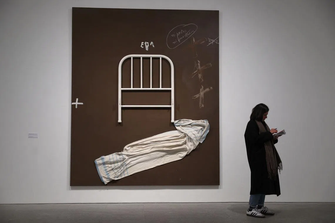 A woman standing next to a piece of art by Spanish artist Antoni Tapies at the Reina Sofia museum in Madrid on Feb 20, 2024. 