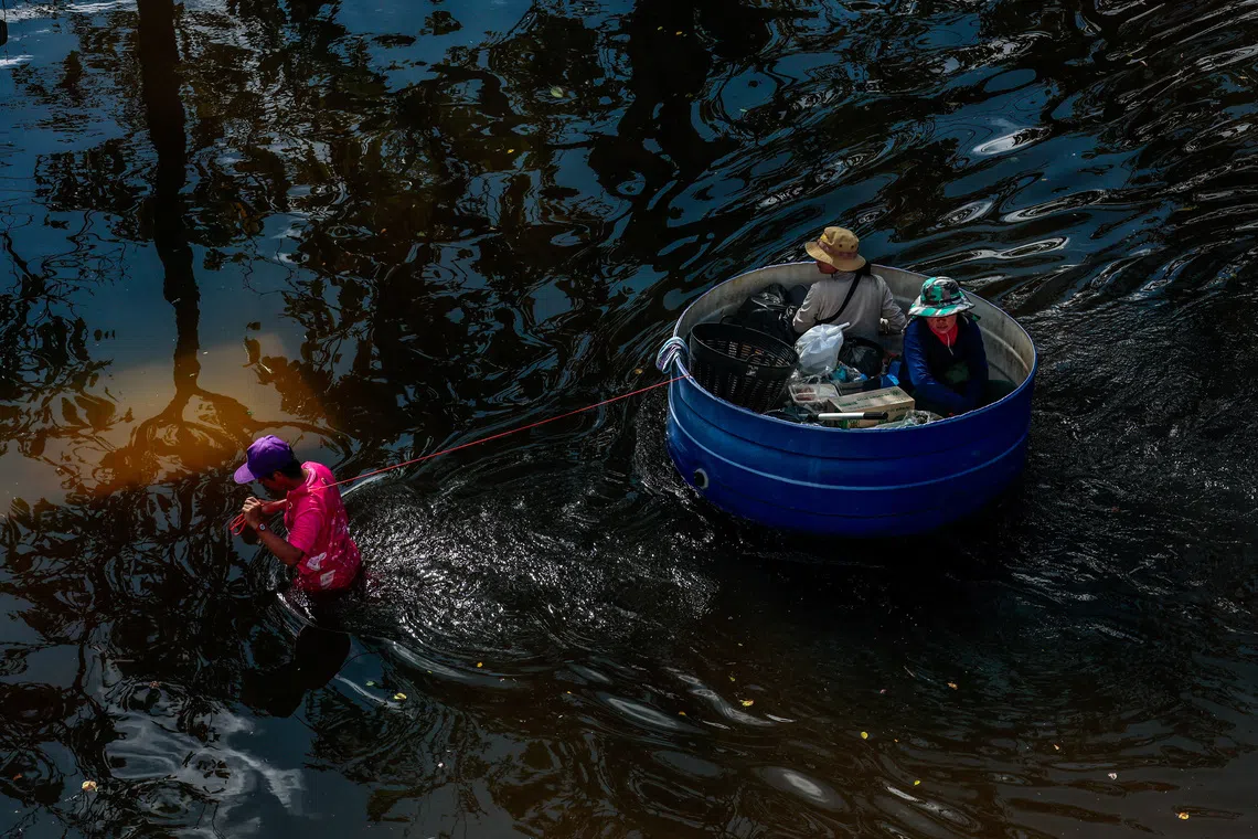 A man pulls a plastic basin carrying people as he navigates the flooded compound of the Sports Authority of Thailand, following heavy rain in Bangkok, Thailand, September 29, 2026. REUTERS/Patipat Janthong TPX IMAGES OF THE DAY