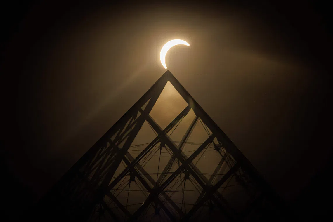 TOPSHOT - The moon passes over the sun's horizon behind the Pyramide du Louvre, designed by Chinese-US architect Ieoh Ming Pei, during a partial solar eclipse in Paris on August 12, 2026. In France, the solar eclipse was not total - after the total solar eclipse of 1999 France will not see another total eclipse for another 55 years in 2081. (Photo by Simon WOHLFAHRT / AFP) / RESTRICTED TO EDITORIAL USE - MANDATORY MENTION OF THE ARTIST UPON PUBLICATION - TO ILLUSTRATE THE EVENT AS SPECIFIED IN THE CAPTION