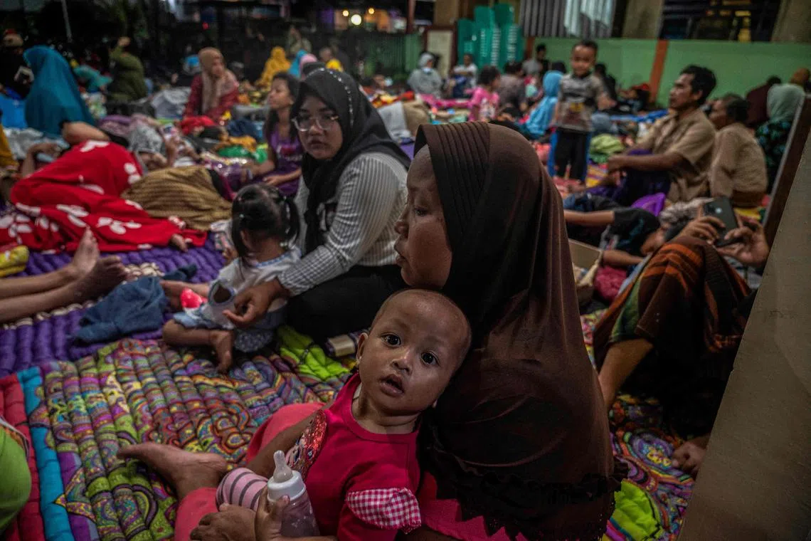 People take temporary shelter in a room at a community hall in Candipuro village following Mount Semeru's volcanic eruption in Lumajang, East Java on Dec 4, 2022. 