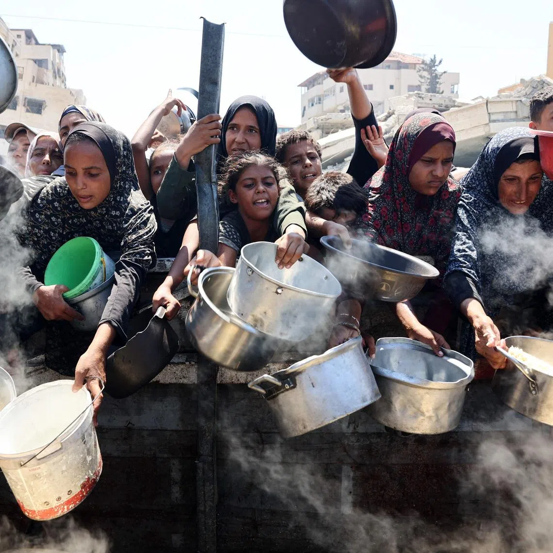 Palestinian women and girls elbow pleading for cooked rice from a charity kitchen in Gaza City on Aug 23.
