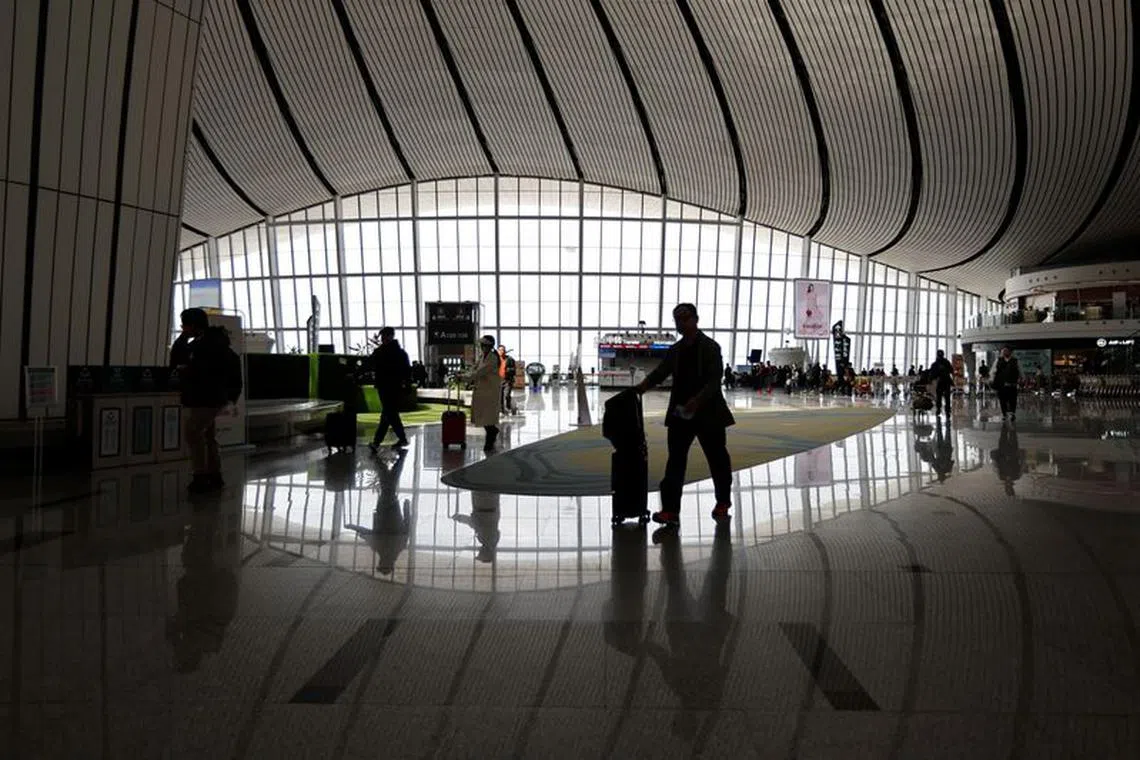 FILE PHOTO: Travellers walk with their suitcases at Beijing Daxing International Airport in Beijing, China April 24, 2023. REUTERS/Tingshu Wang/File photo