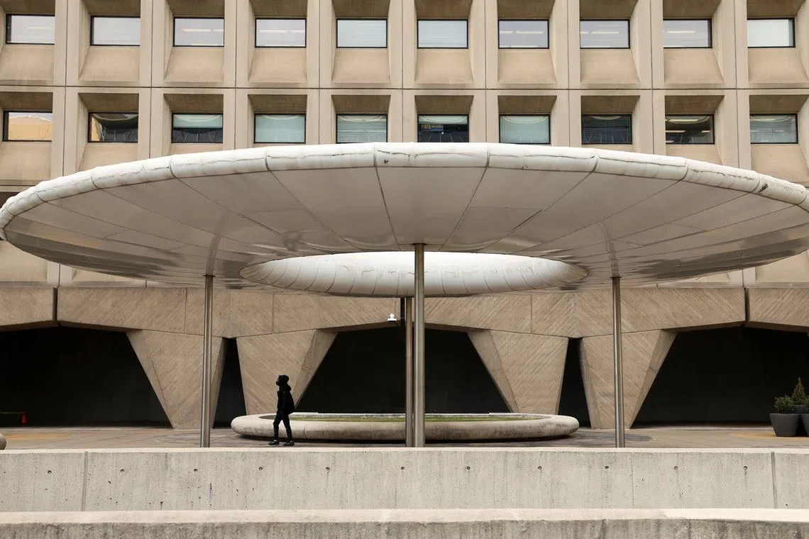 A person walks under a shade canopy in front of the headquarters of the Federal Department of Housing and Urban Development (HUD), days after U.S. President Donald Trump offered buyouts to thin the ranks of civil-service workers, in Washington, U.S., February 3, 2025. REUTERS/Kevin Lamarque/File Photo