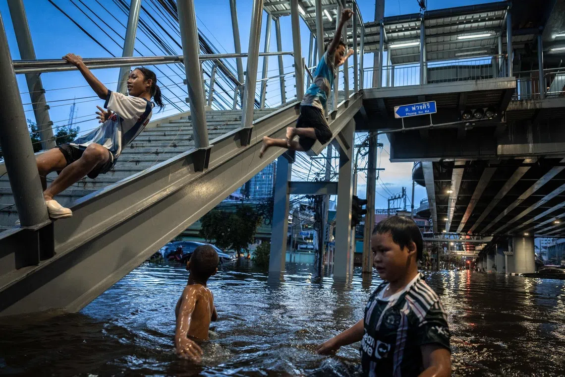 TOPSHOT - Children play in the floodwater in the Bang Kapi district of Bangkok on September 28, 2026. More than 500,000 households and 1.7 million people across 27 provinces are currently affected by floods in Thailand after an intense weather system hit the region, the government said. (Photo by Chanakarn LAOSARAKHAM / AFP)