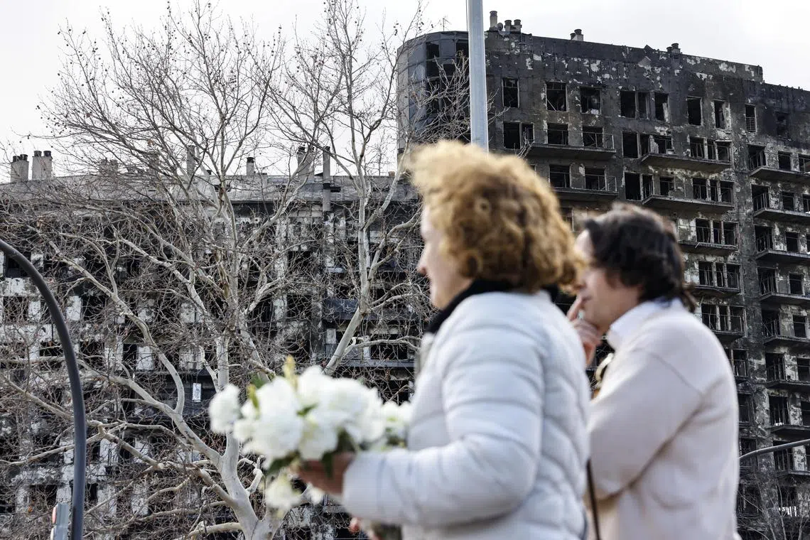 epa11177479 Two women lay flowers in front of the affected condominiums in Valencia, Spain, 24 February 2024. At least ten peope died when  fire on 22 February ripped through two apartment blocks.  EPA-EFE/Ana Escobar