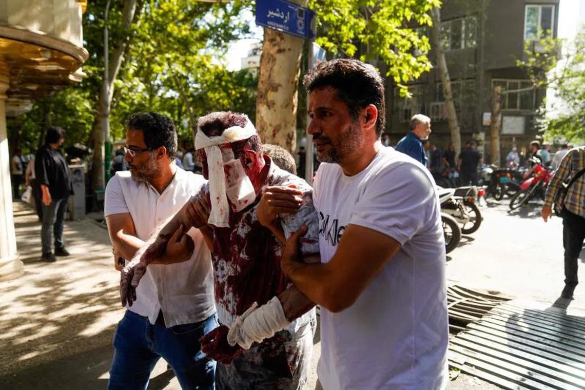 Iranians care for a man who was injured in a reported Israeli strike on Keshavarz Boulevard in downtown Tehran on June 15, 2025. Israel and Iran traded heavy fire for a third straight day on June 15, with mounting casualties and expanding targets marking a sharp escalation in hostilities between the longtime foes. (Photo by AMIR KHOLOUSI / ISNA / AFP)