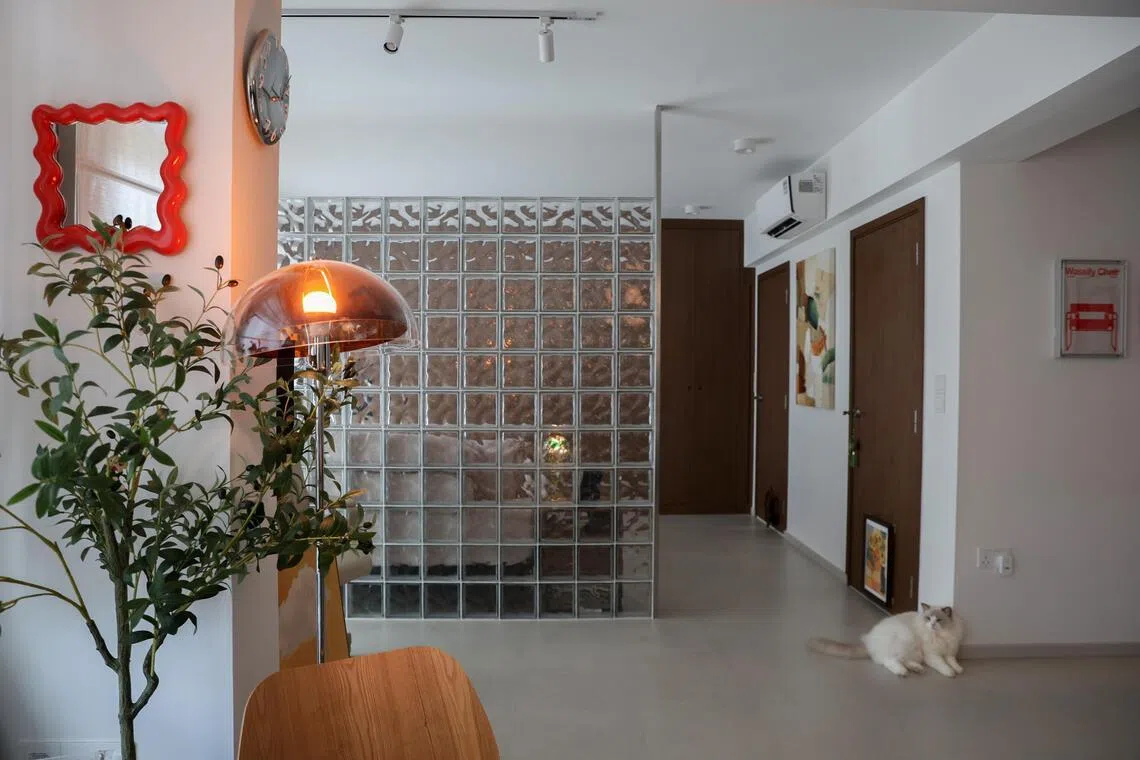 A glass brick feature wall separates the living room from the bedroom in married couple Fiona Ng and Tan Shao Wei’s home.