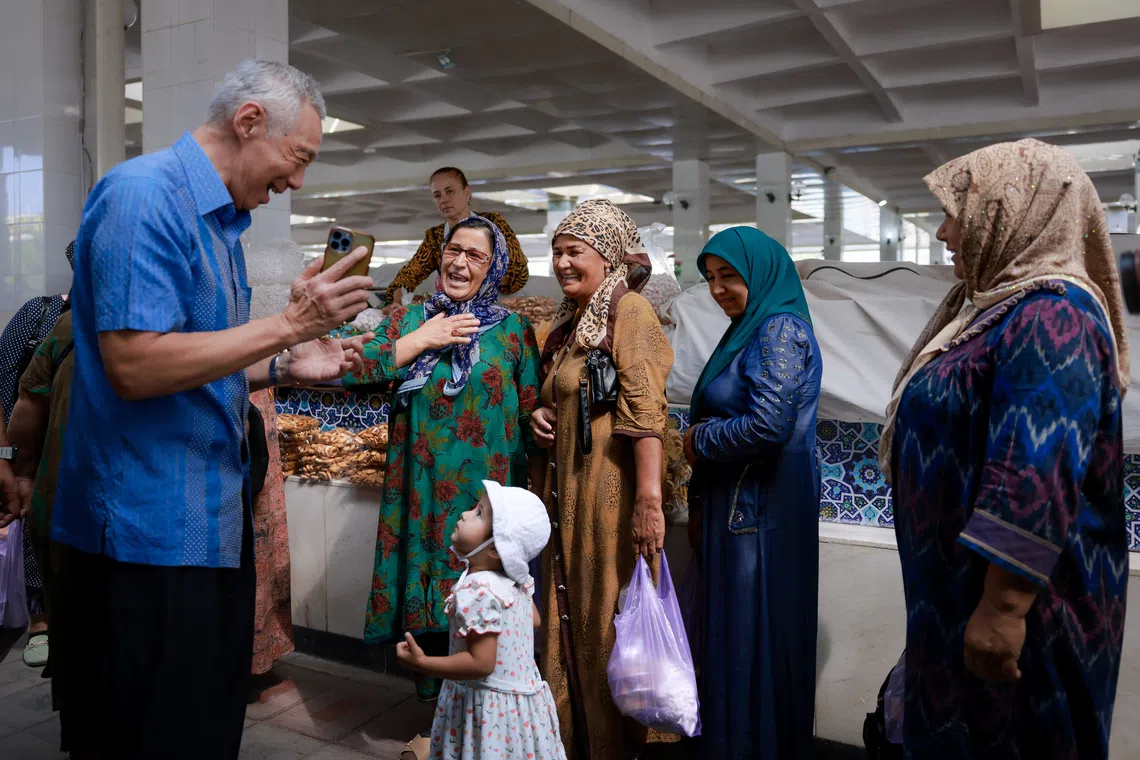 Senior Minister Lee Hsien Loong photographs local shoppers as he walks through Siyob Bazaar in Samarkand, Uzbekistan, on Aug 30.