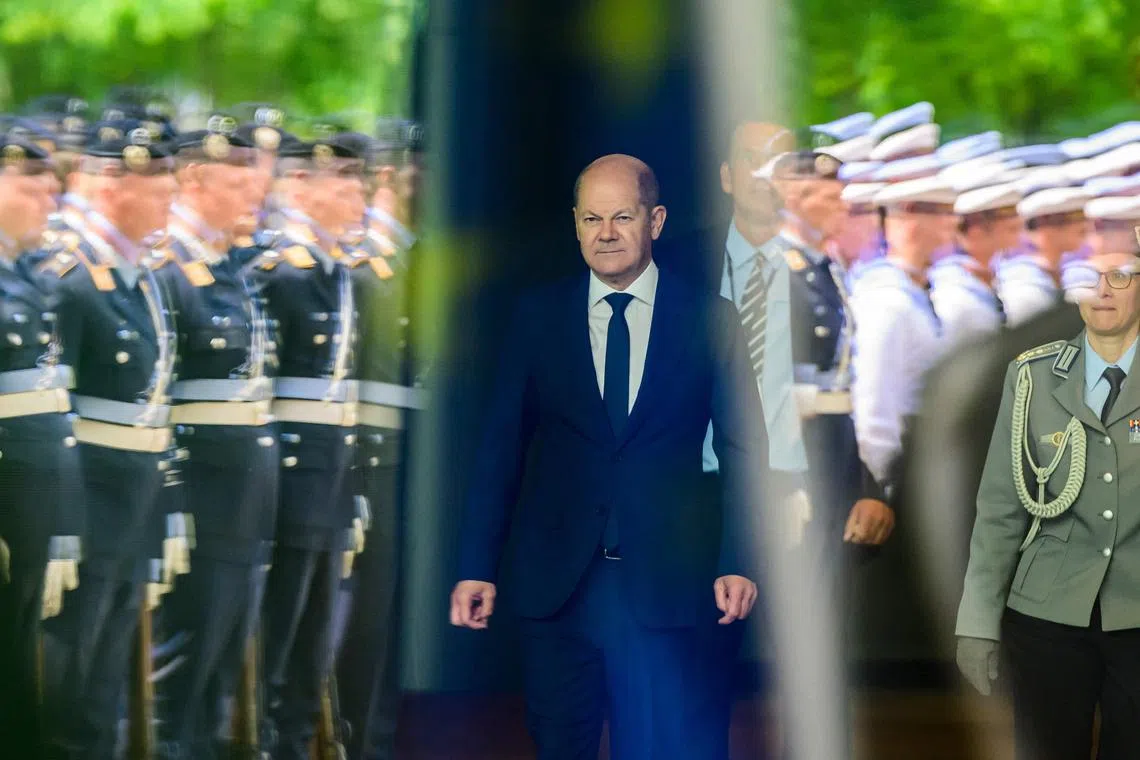 TOPSHOT - German Chancellor Olaf Scholz walks out of the chancellery to greet the President of Cyprus, as a German honour guard is reflected in the glass facade of the building in Berlin on May 25, 2023. (Photo by John MACDOUGALL / AFP)