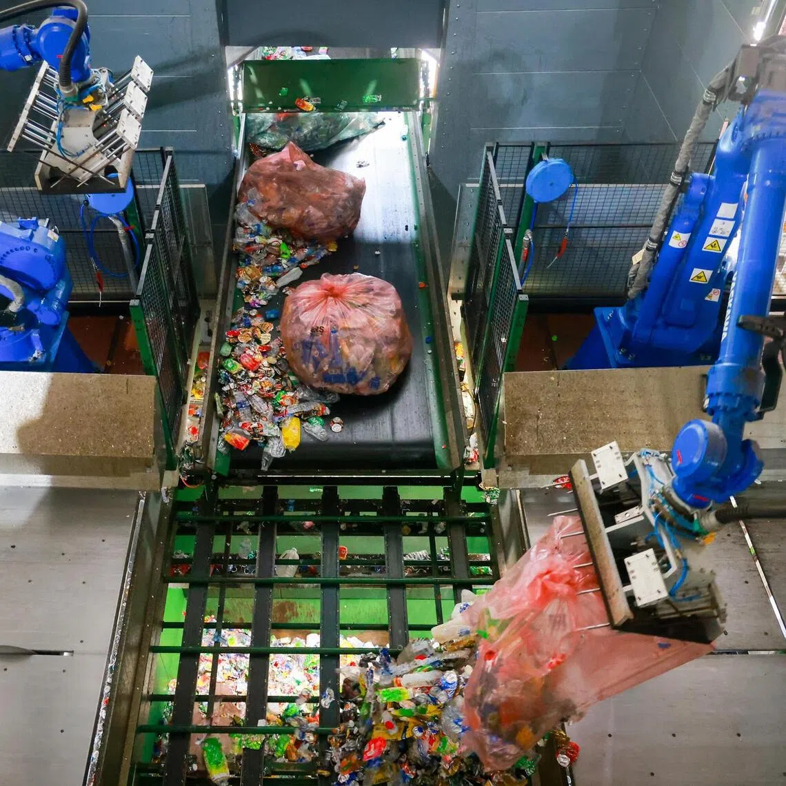 Robotic arms release the flattened bottles and cans into a heavy-duty storage bin, to kickstart the sorting process at the facility.