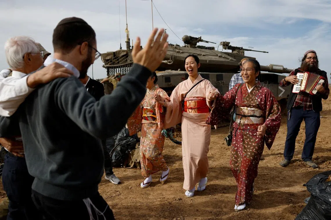 Japanese supporters dancing with Israeli soldiers in an effort to raise morale, amid the ongoing conflict between Israel and the Palestinian group Hamas, near Israel's border with Gaza in southern Israel, Nov 22, 2023. 