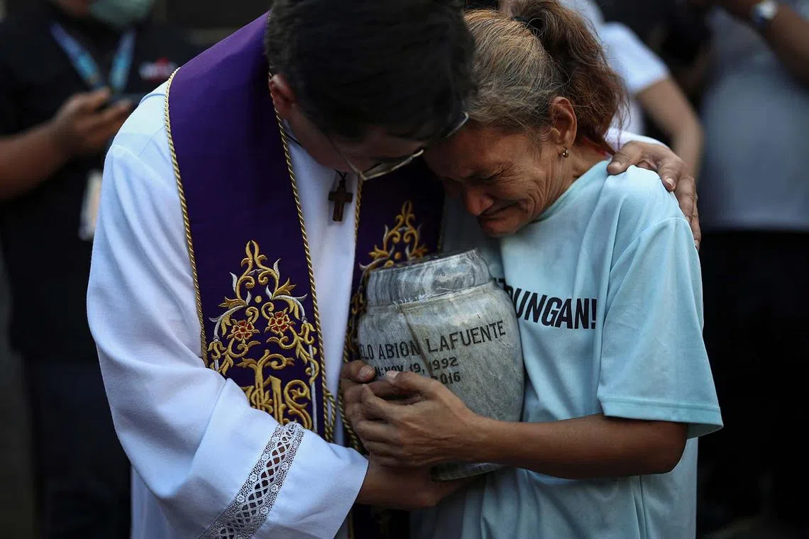 Catholic priest Flavie Villanueva embracing Melinda Lafuente as she holds the urn with the remains of her son Angelo Lafuente, during an interment ceremony for victims of extrajudicial killings, at the Dambana ng Paghilom (Shrine of Healing) in Caloocan City, Metro Manila, Philippines, March 12, 2025. 