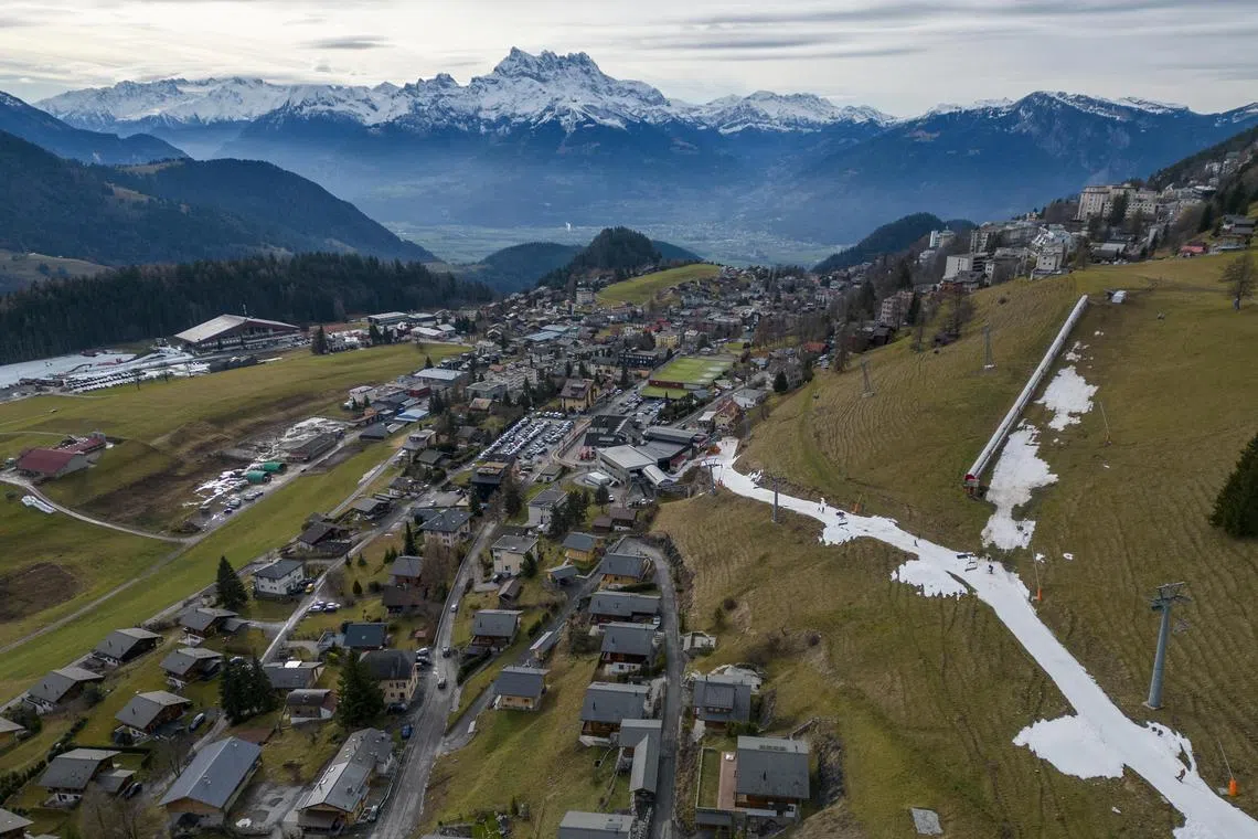 Skiers pass on a small layer of artificial snow amid warmer-than-usual winter temperatures in the Alps in Leysin, Switzerland.
