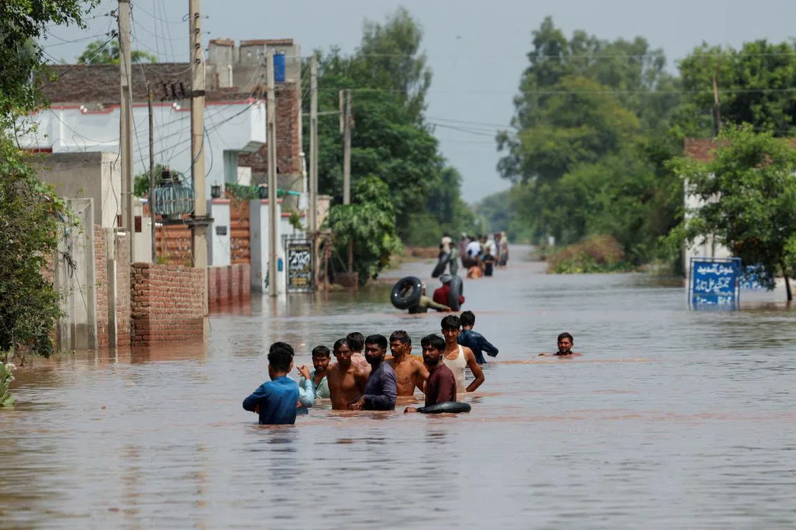 Residents wade through a flooded road, following monsoon rains and rising water levels in Qadirabad village near the Chenab River in Punjab province, Pakistan August 28, 2025. REUTERS/Akhtar Soomro
