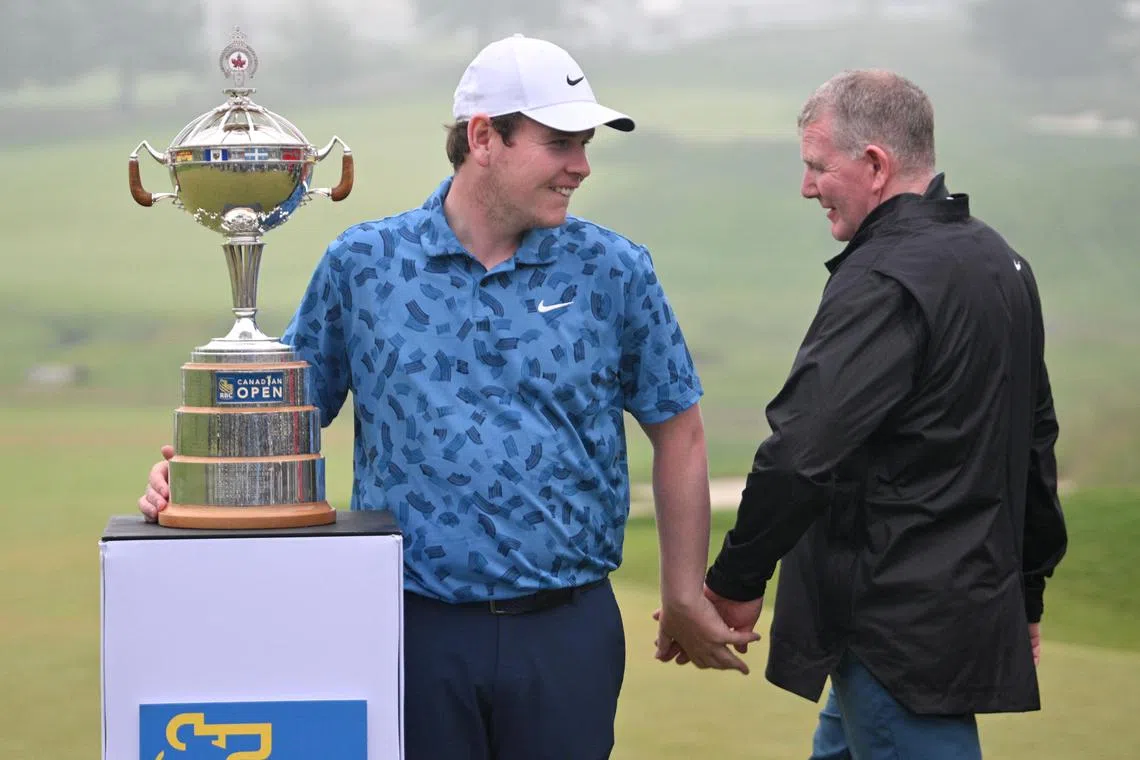 Robert MacIntyre slapping hands with his father Dougie, who filled in as his caddie for the tournament, as they set up for trophy photos after winning the Canadian Open golf tournament in Hamilton, Ontario, on June 2.