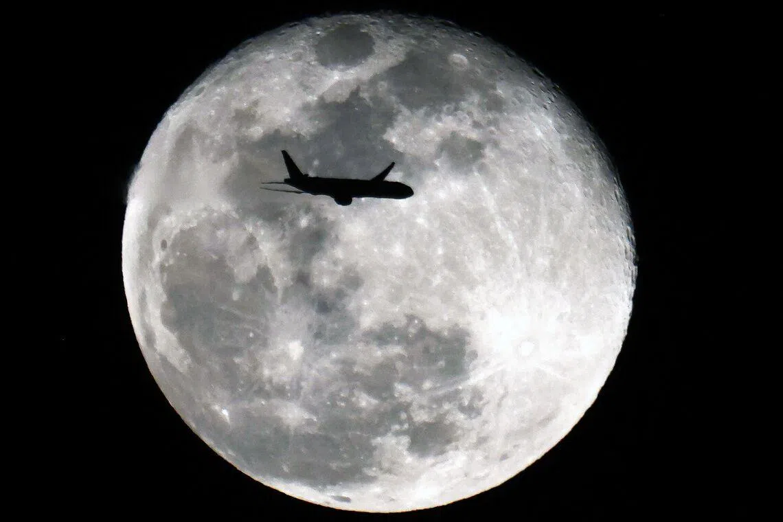 TOPSHOT - An Boeing 777-369 (ER) Kuwait Airways aircraft headed to Mumbay, India, is silhouetted against the Waning Gibbous moon above Kuwait City on January 4, 2026. (Photo by YASSER AL-ZAYYAT / AFP)