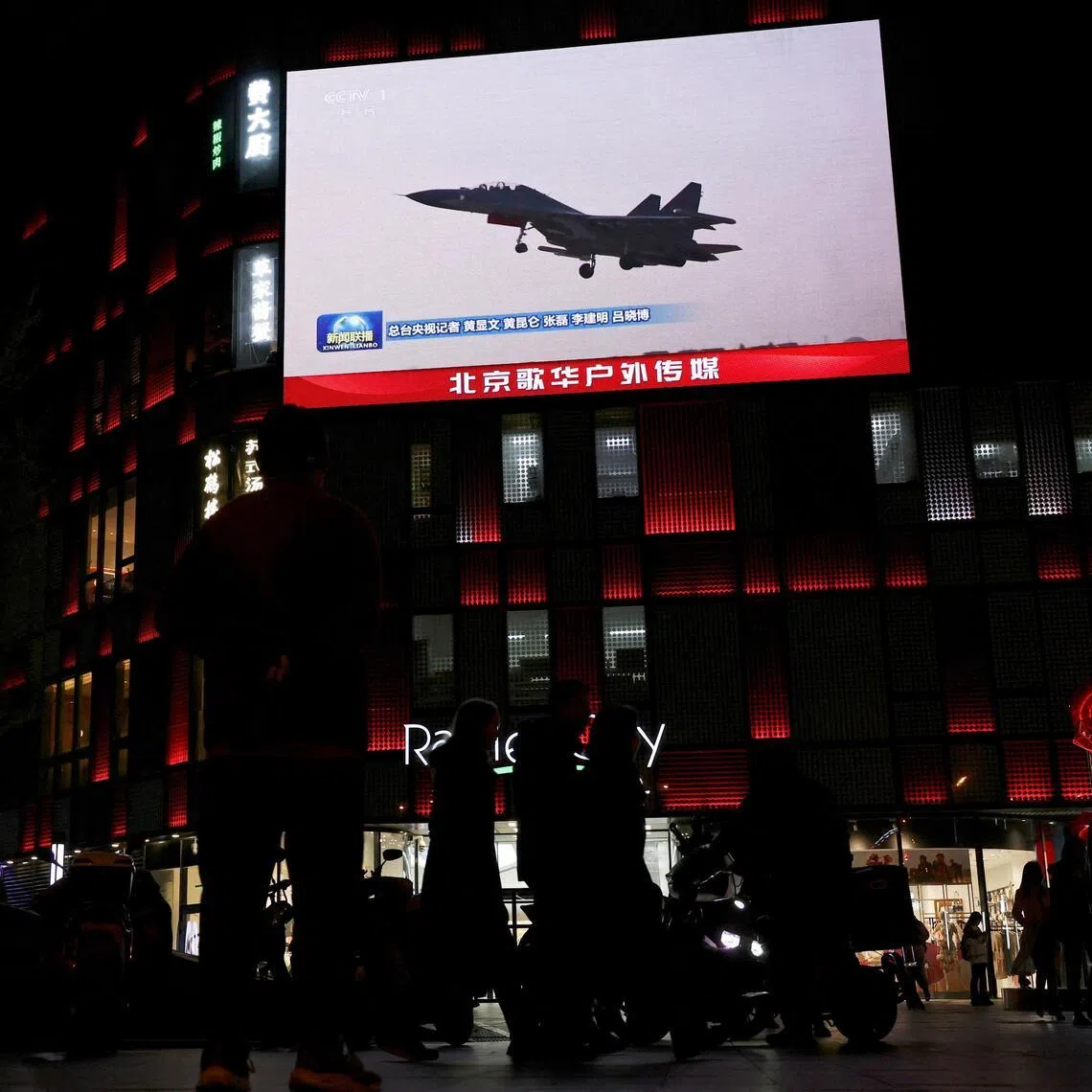 A military aircraft is seen on a giant screen showing news footage about joint army, navy, air and rocket forces drills around Taiwan by the Chinese Army, outside a shopping mall in Beijing.
