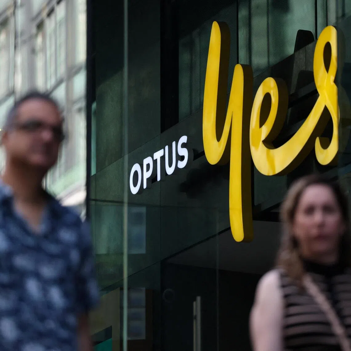 People walk past an Optus store in Sydney, Australia, September 29, 2025. REUTERS/Hollie Adams