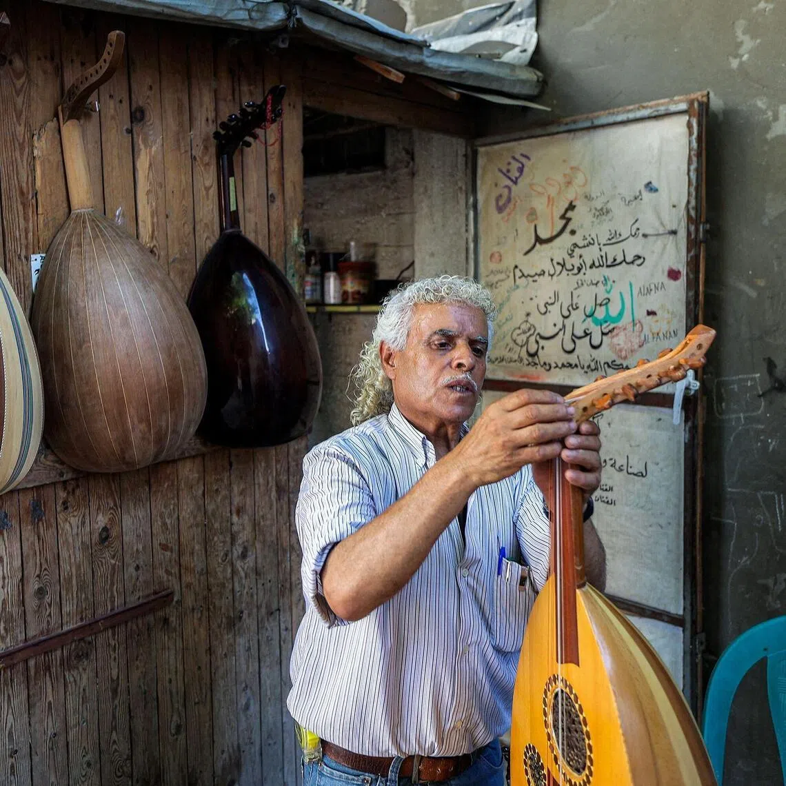 Palestinian craftsman Suhail Abu Shawish tuning a damaged oud – a stringed instrument considered the ancestor of the European lute – at his makeshift workshop in the central Gaza Strip.