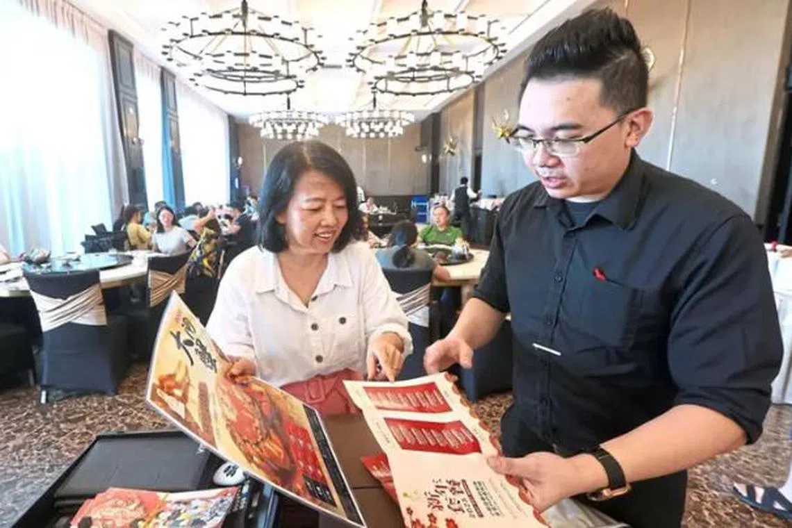 Restaurant manager Jacky Goh briefing a customer about his restaurant’s Chinese New Year reunion meal packages in Johor Bahru.