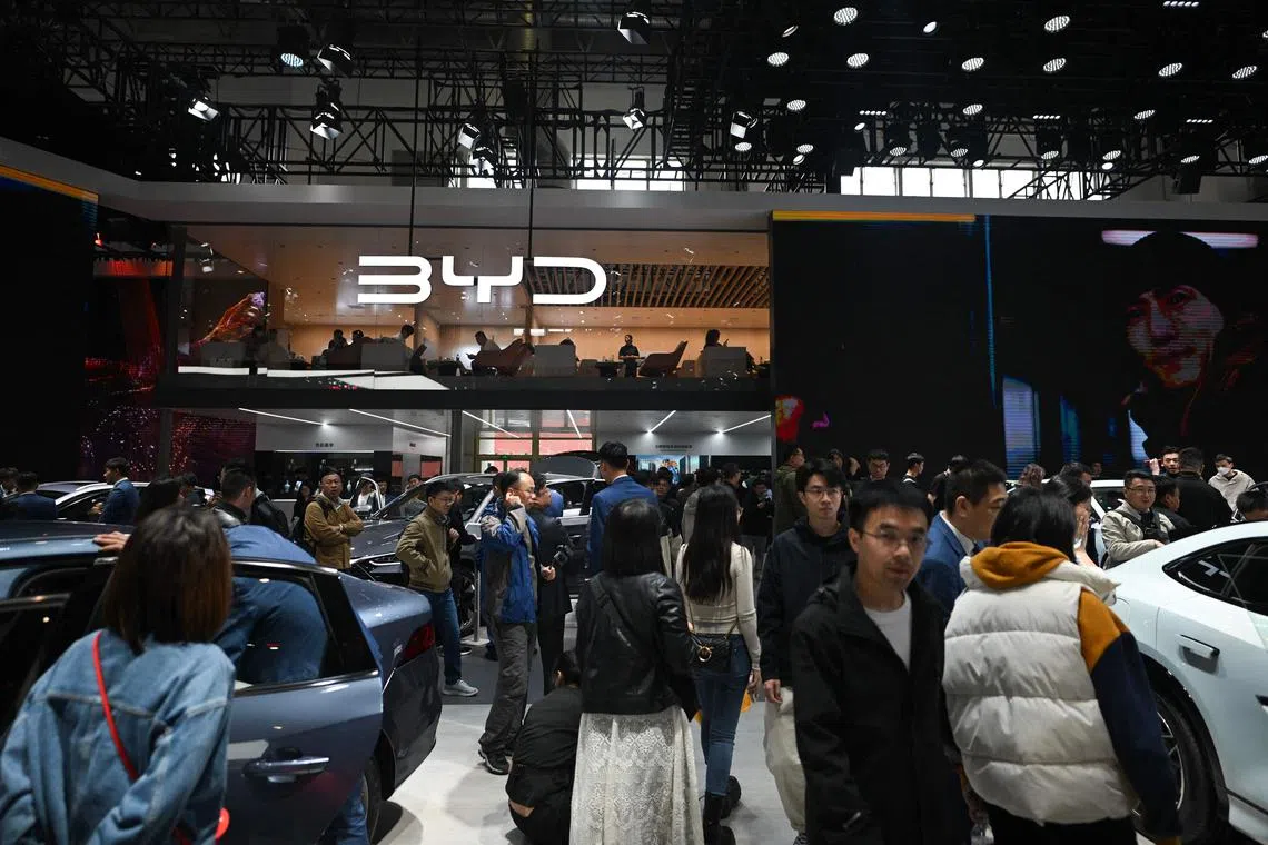 (FILES) This photo taken on April 29, 2024 shows people visiting the BYD stand at the Beijing Auto Show in Beijing. Struggling foreign automakers in China are looking for help from local tech giants to try and stay competitive in the world's biggest electric car market, where shiny smart screens, assisted driving and sophisticated map technology are in high demand. (Photo by Pedro PARDO / AFP) / To go with China-economy-auto-technology-EVs, FOCUS by Peter Catterall and Qasim Nauman