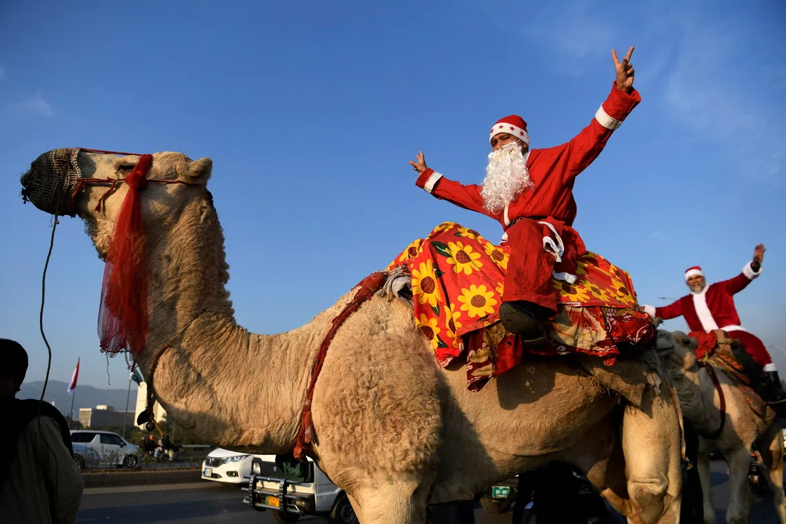 A member of Pakistan's Christian minority dressed as Santa Claus riding a camel along a road during a rally ahead of Christmas, in Islamabad, Pakistan, on Dec 7, 2025. 