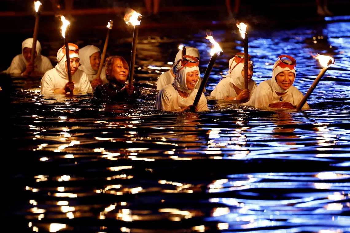 FILE PHOTO: \"Ama\" female free divers, who harvest sea life from the ocean, lead volunteers as they swim with torches during Shirahama Ama matsuri in Minamiboso, Chiba Prefecture, Japan July 20, 2024. REUTERS/Kim Kyung-Hoon/File Photo