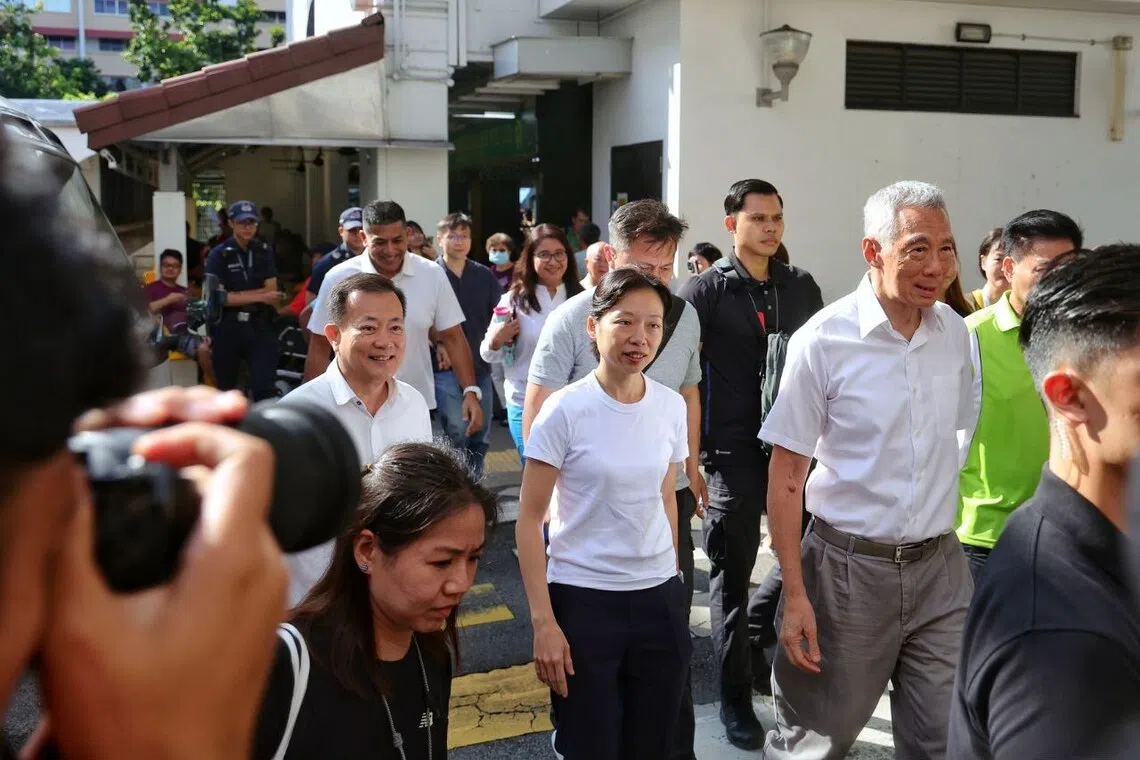 PAP new faces Health Ministry deputy secretary for policy Jasmin Lau and Victor Lye arriving with Senior Minister Lee Hsien Loong at Hougang Village on April 13. 