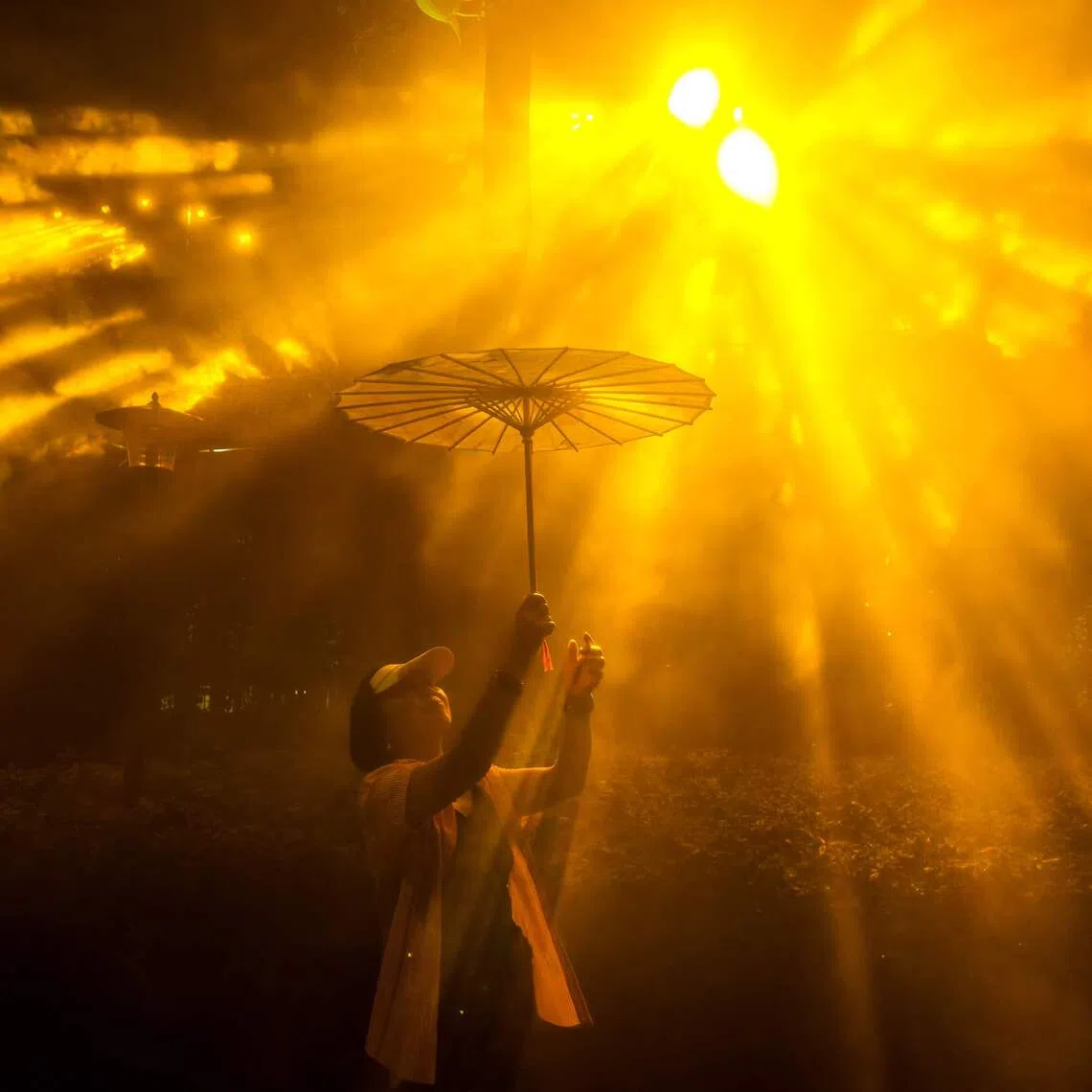 TOPSHOT - A woman holding an umbrella poses for a picture as she visits the Shanghai International Light Festival in a park in Shanghai on September 17, 2026. (Photo by CN-STR / AFP) / China OUT