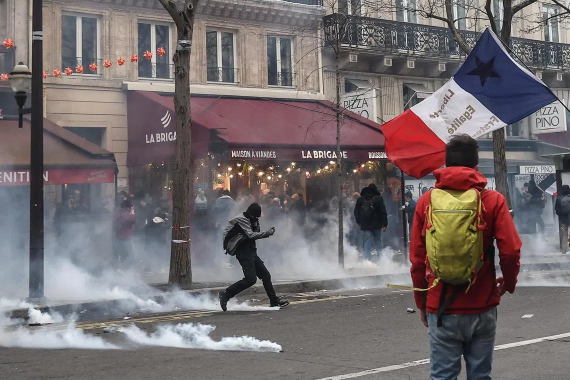 A protester kicks a tear gas bomb during clashes with anti-riot police,  in Paris, on March 23, 2023.