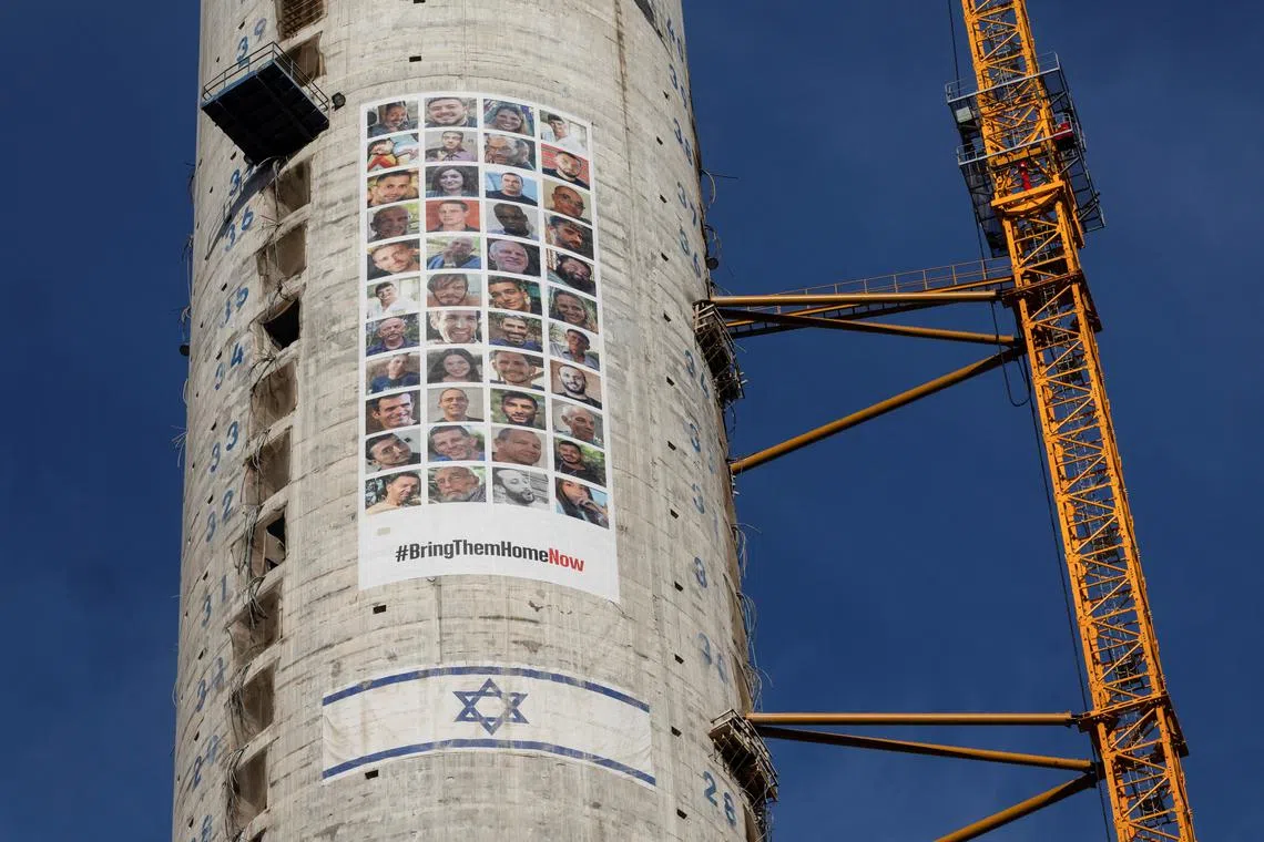 FILE PHOTO: Pictures of hostages kidnapped during the deadly October 7 attack by the Palestinian Islamist group Hamas from Gaza, are seen next to an Israeli flag on a building under construction, in Tel Aviv, Israel, May 31, 2024. REUTERS/Marko Djurica/File Photo