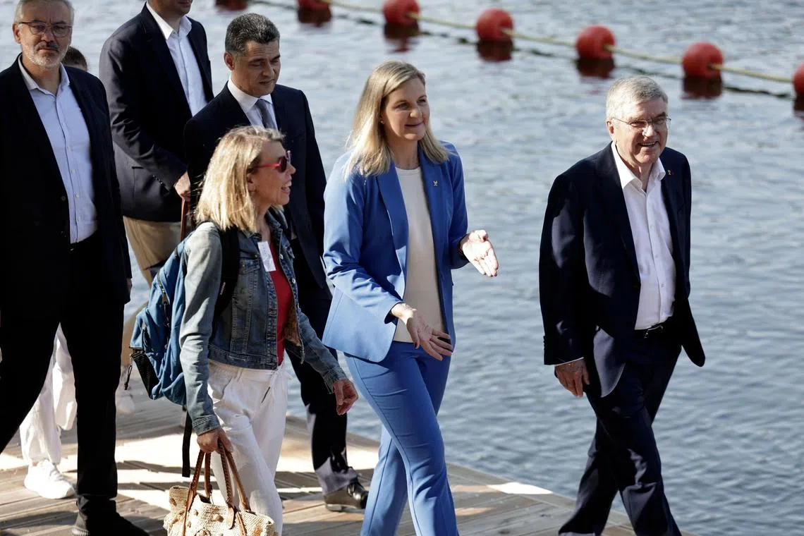 President of the International Olympic Committee Kirsty Coventry (C) and her predecessor Thomas Bach (R) walk towards the bras Marie area along the Seine river during the celebrations marking the first anniversary of the Paris 2024 Olympic Games in Paris on July 26, 2025. (Photo by STEPHANE DE SAKUTIN / POOL / AFP)
