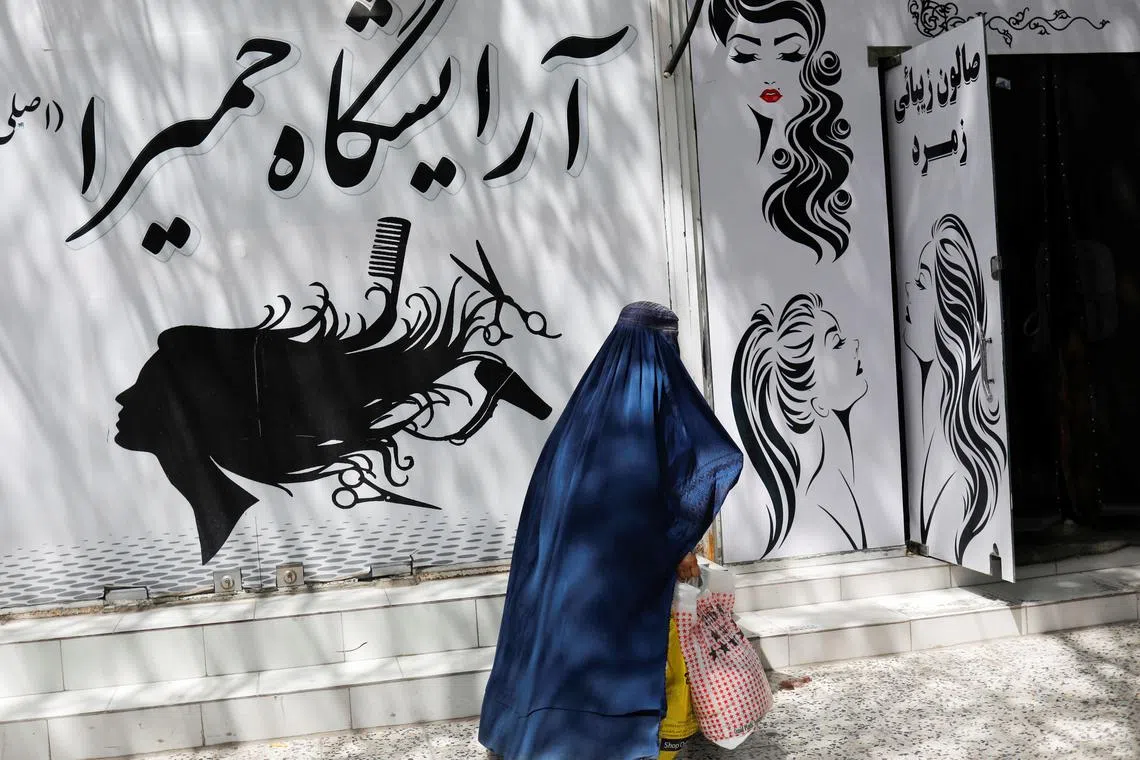 FILE PHOTO: An Afghan woman walks past a beauty salon in Kabul, Afghanistan, July 6, 2023. REUTERS/Ali Khara/File Photo