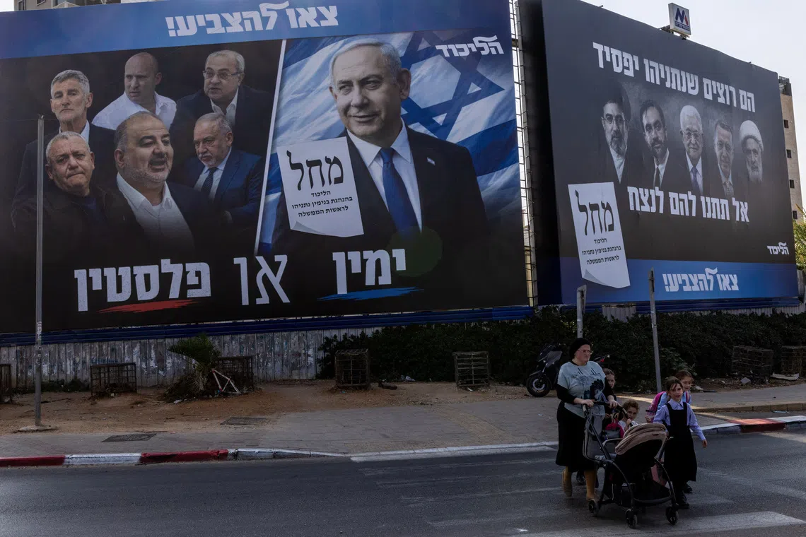 People walk next to a campaign banner of Netanyahu's Likud party, ahead of the Israeli parliamentary election, in Bnei Brak, Israel, October 25, 2026. REUTERS/Nir Elias