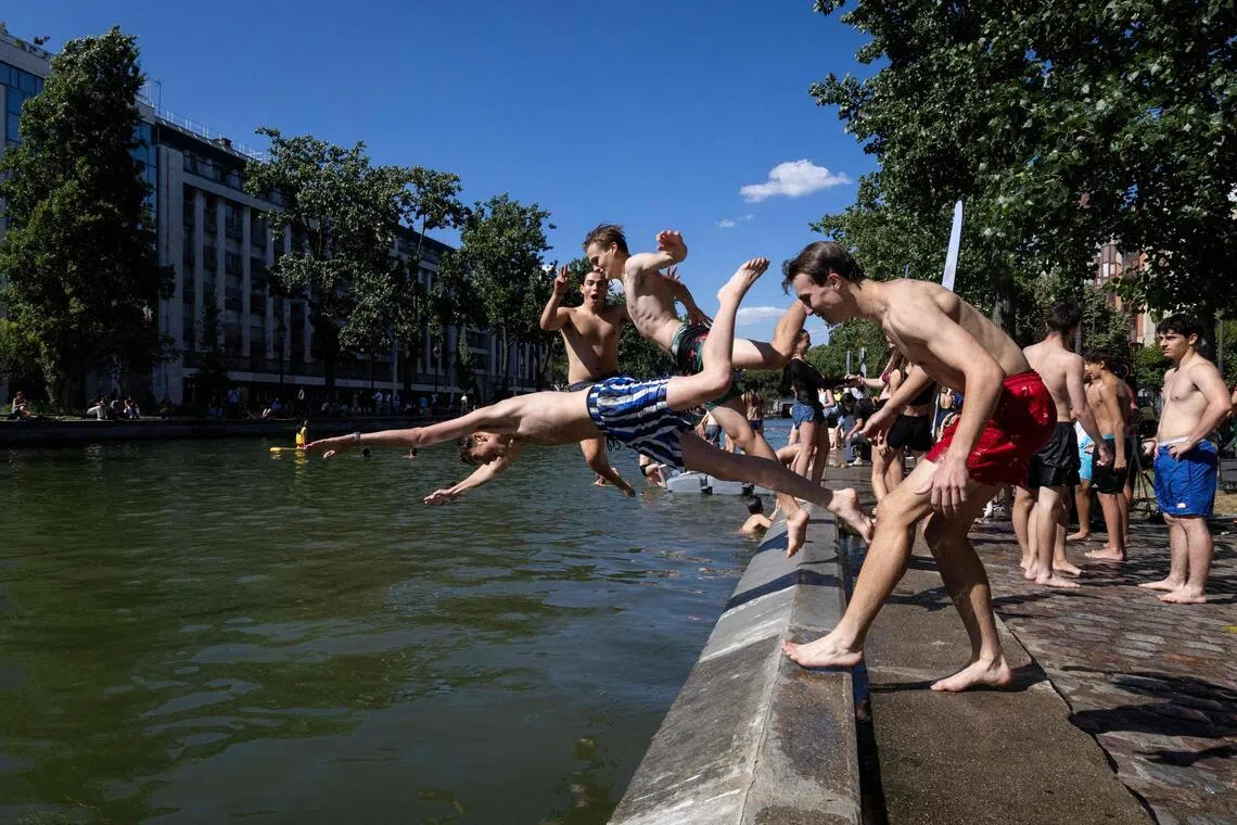 Young people dive into the Bassin des Recollets on the Canal Saint-Martin in Paris on June 17, 2026.  