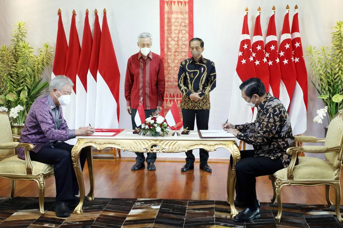 PM Lee Hsien Loong and Indonesian President Joko Widodo looking on as Senior Minister Teo Chee Hean (seated, left) and Indonesian Coordinating Minister for
Maritime Affairs and Investments Luhut Pandjaitan sign an exchange of letters undertaking to bring three agreements into force at the same time, at the Leaders’
Retreat in Bintan in January 2022.