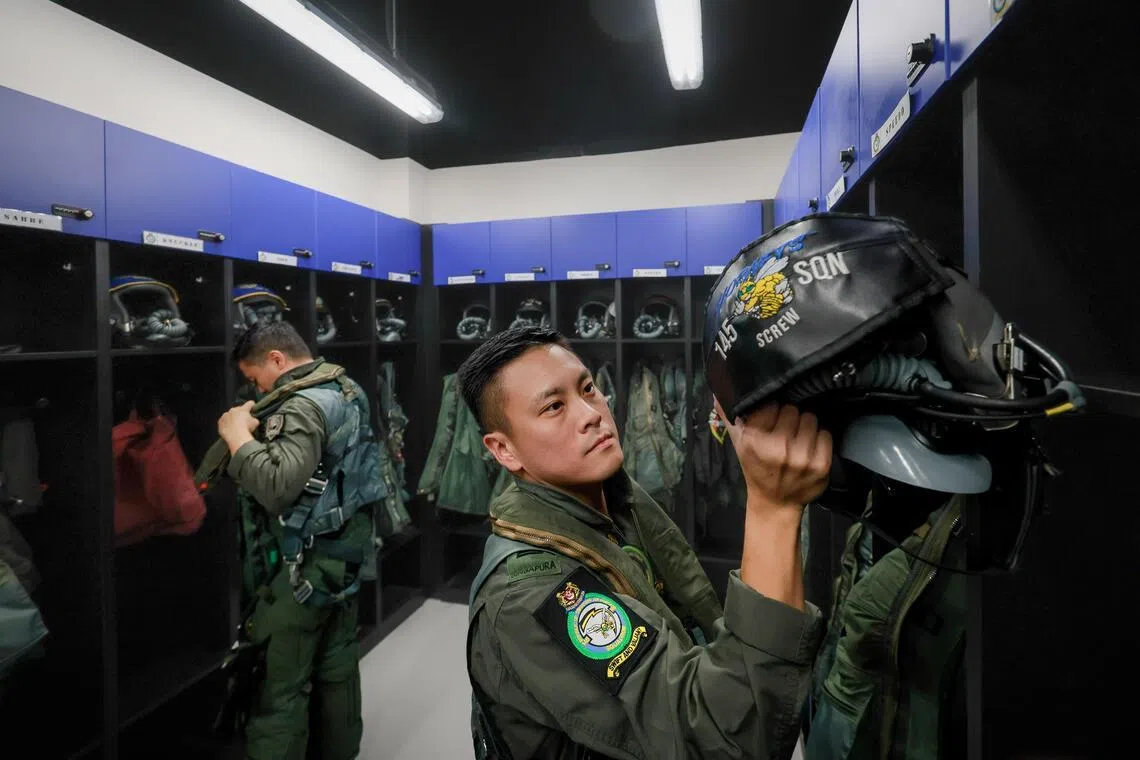 Weapon systems officer Captain Cheong Kah Fai (right) and pilot Major Ng Cheong Leong preparing for a flight in a kit room at Tengah Air Base on June 24. The two men are F-16 aircrew from 145 Squadron and also serve as instructors.