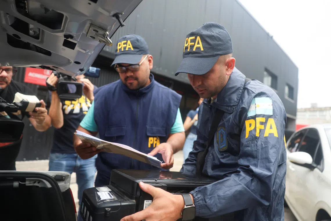 A member of the Argentine Federal Police places a printer inside the trunk of a car after seizing it from Claudio Chiqui Tapia stadium, which belongs to the soccer team Barracas Central, where Federal Police raid amid investigation into alleged money laundering, according to local media, in Buenos Aires, Argentina, December 9, 2025. REUTERS/Cristina Sille