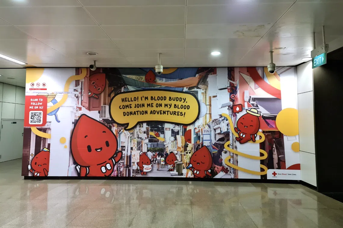 a mural at bugis mrt station featuring blood buddy, the blood donation mascot reimagined by akin by techlyon for the singapore red cross to better connect with younger audiences