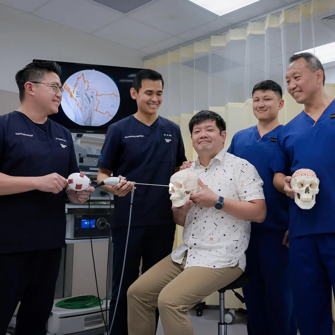 The team that carried out the eight-hour transorbital neuroendoscopic surgery (TONES) on patient Teong Wen Han (centre): Ophthalmologist David Law and otolaryngoloist Tan Jian Li from Tan Tock Seng Hospital; and neurosurgeons Jensen Ang and Christopher Ang from the National Neuroscience Institute.