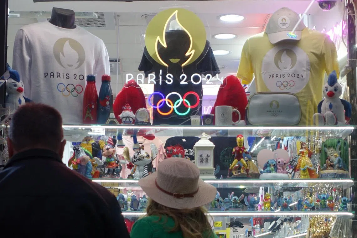 People outside a shop at Champs-Elysees avenue with souvenirs advertising the Paris 2024 Olympic and Paralympic Games in France on July 6.