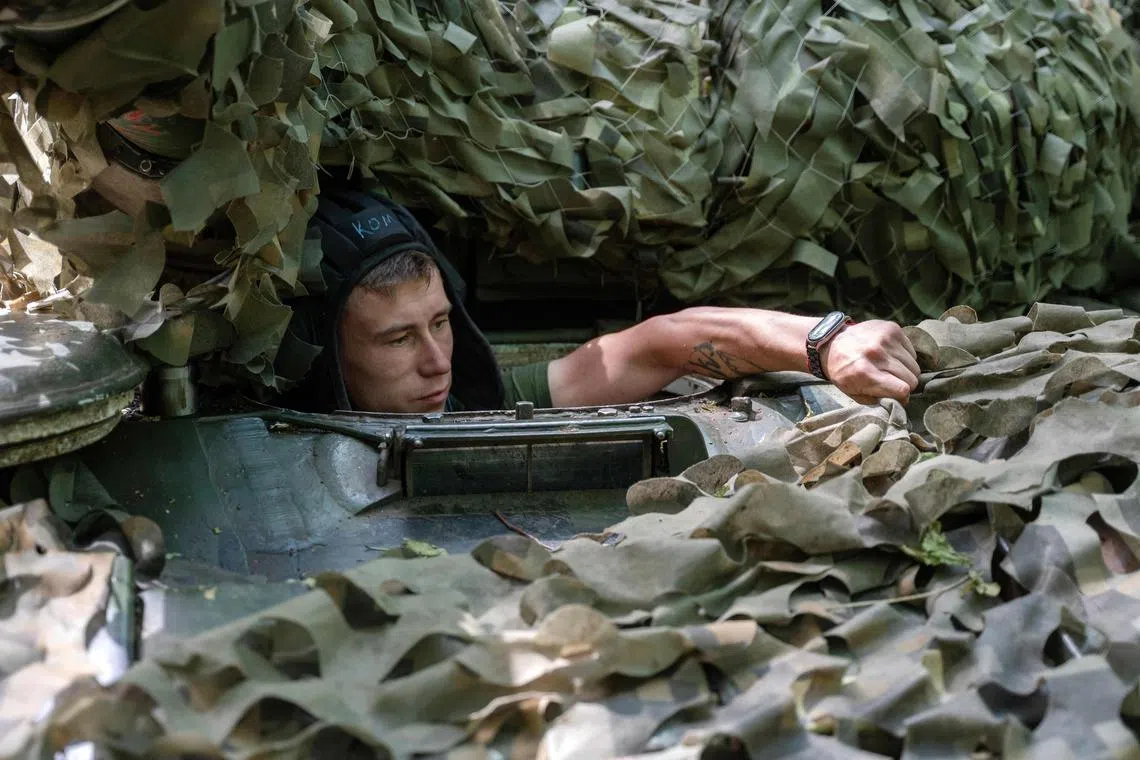 A Ukrainian serviceman of the 3rd Independent Tank Iron Brigade looks out of a tank hatch at a position near the front line, in Ukraine's Kharkiv region.